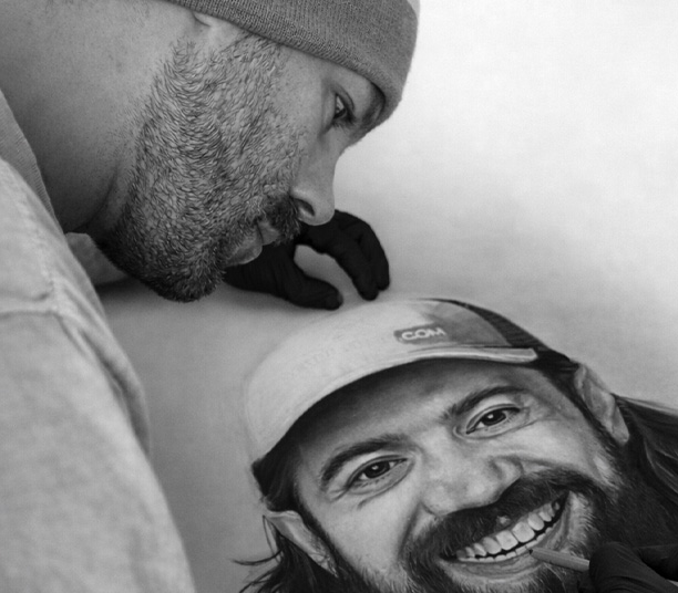 man closely examining a detailed black and white portrait of another man smiling wearing a cap emphasizing artistry and creativity six expressions